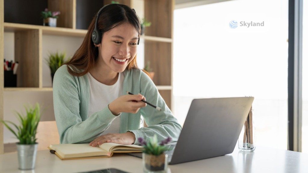 A student wearing headphones and studying for IELTS Academic Training on a laptop