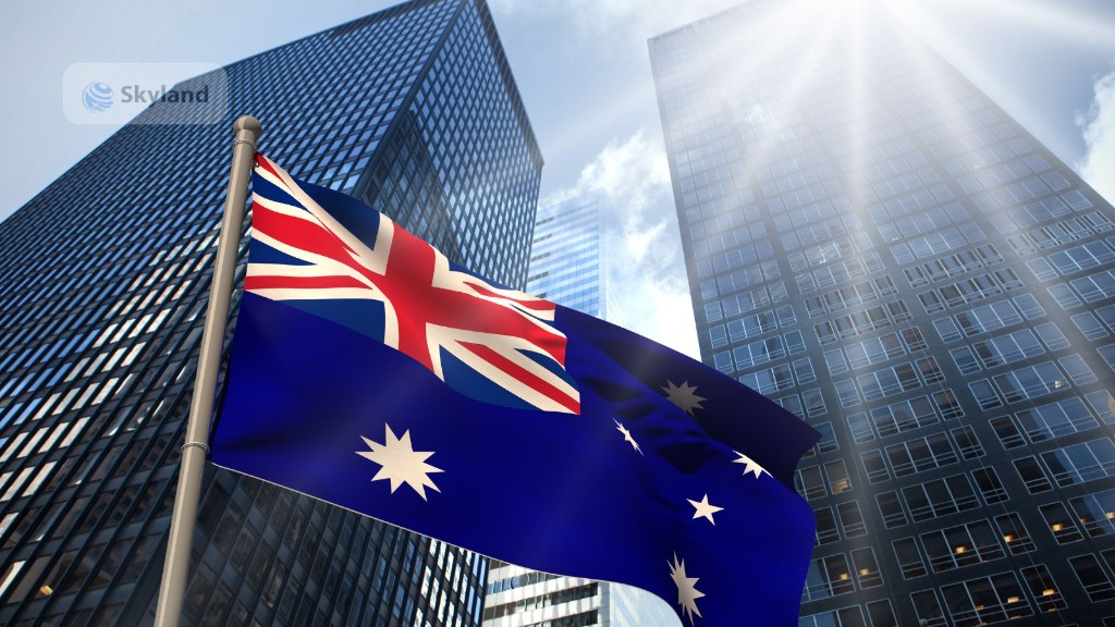 Australian flag waving in front of city skyscrapers