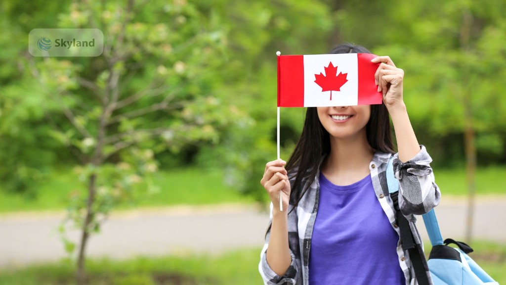 Student smiling while holding a Canadian flag